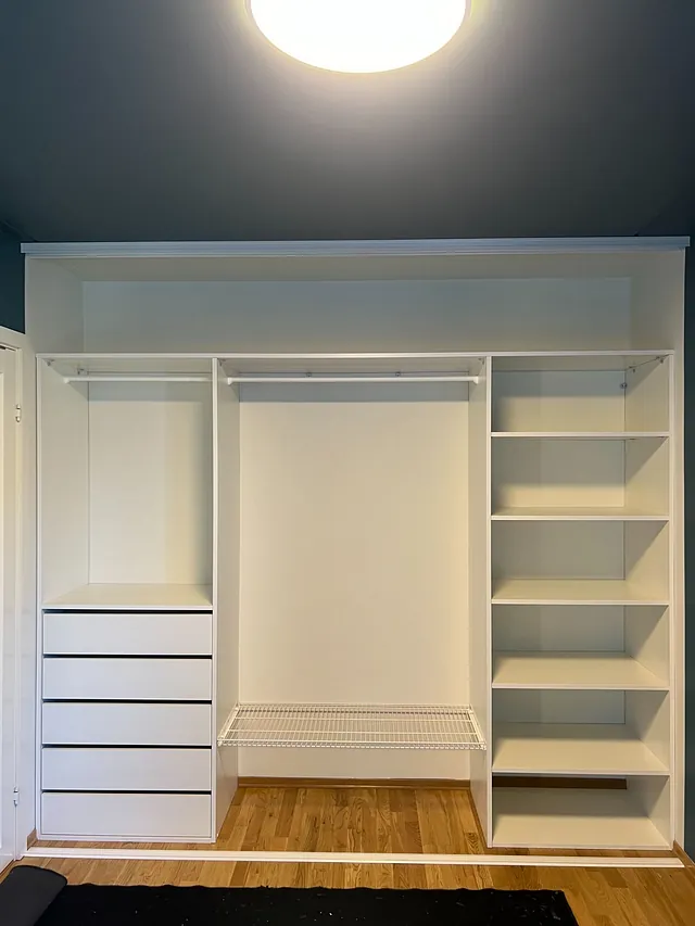Garderobe med fire skuffer, trådhyller og åpne seksjoner for klær.