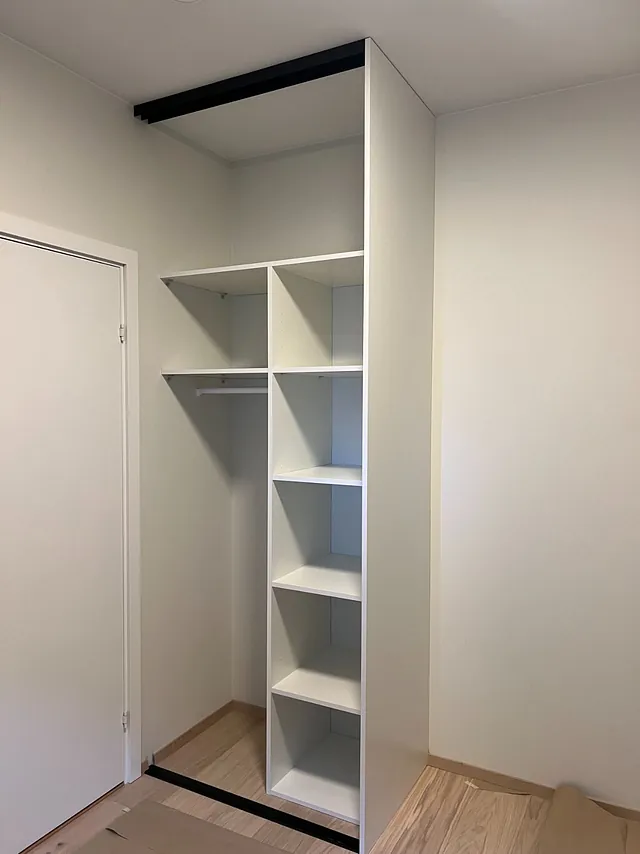 Smal garderobeløsning med åpne hyller og en hengestang på siden.
