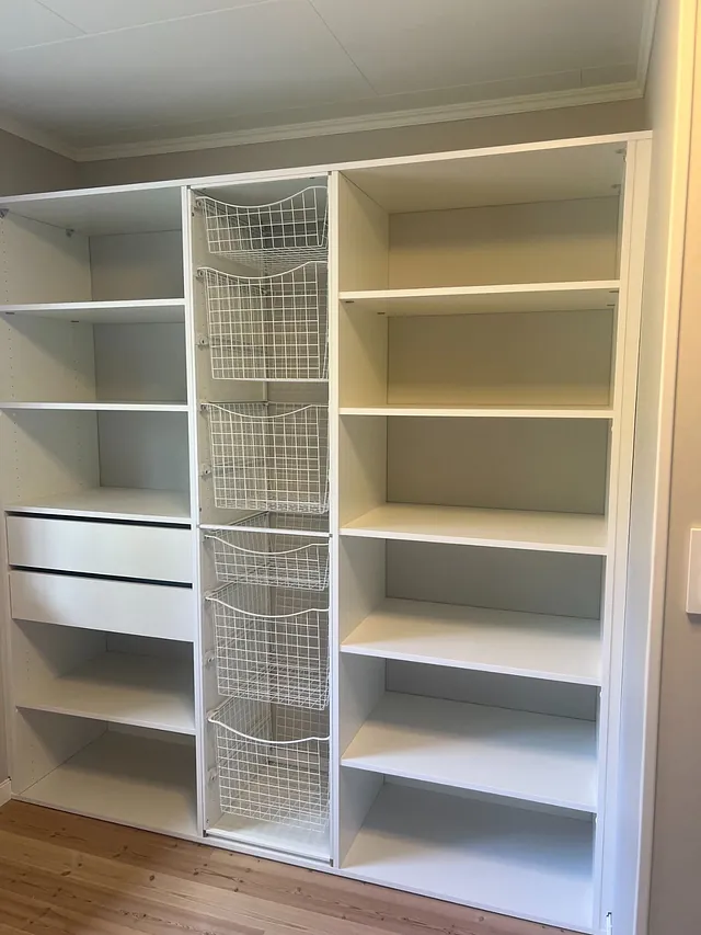 Garderobe med hyller, to skuffer og flere trådkurver i midtseksjonen.